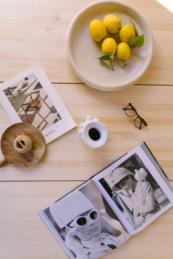 Top view of a natural wood table styled with lemons, magazines, and decorative objects, reflecting the calm and curated aesthetic of Japandi interiors.